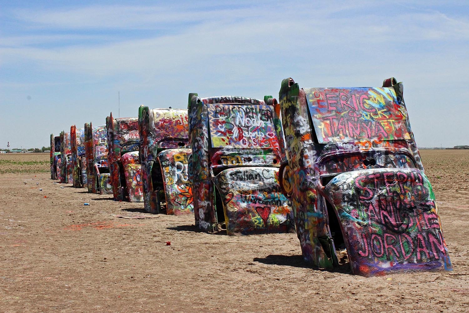 A row of graffiti-covered Cadillacs half buried in the ground at Cadillac Ranch